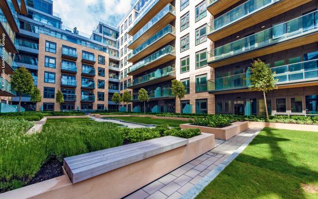 Courtyard with benches, lawn and small trees surrounded by residential blocks